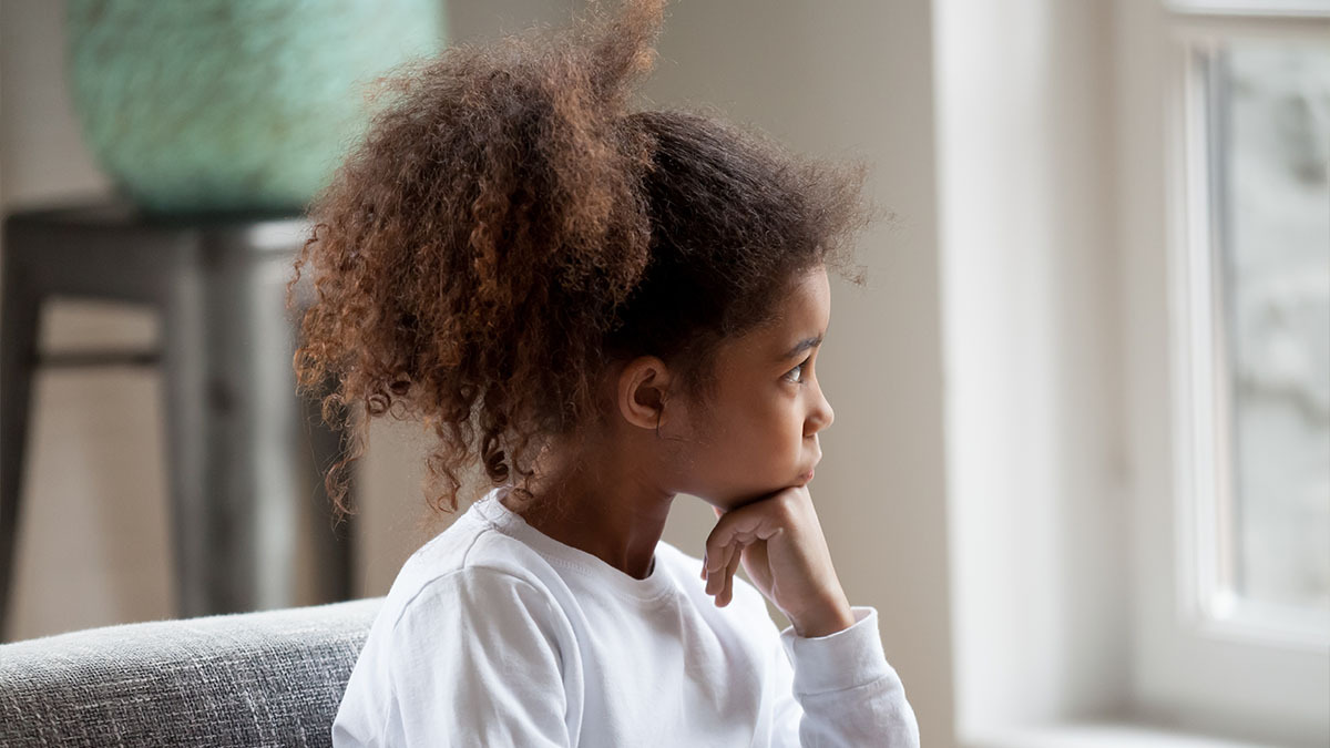 A little girl stares out a window in thought