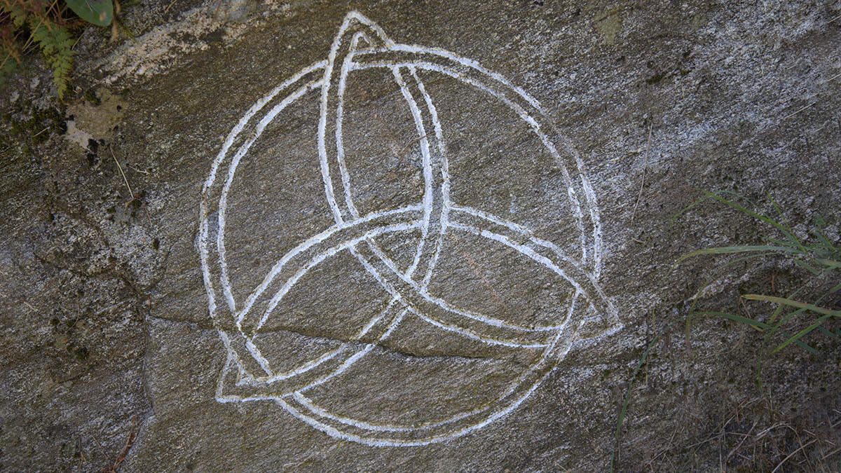 A symbol representing the trinity is drawn on a rock