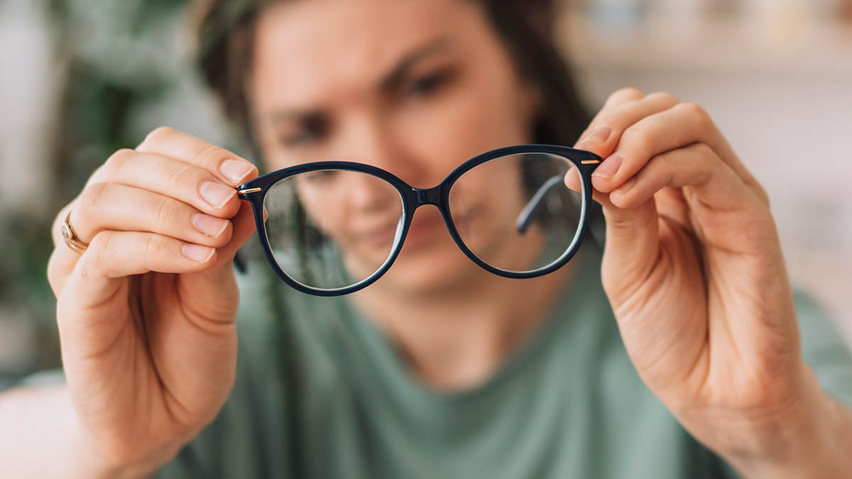 A woman holds up a pair of glasses in front of her face