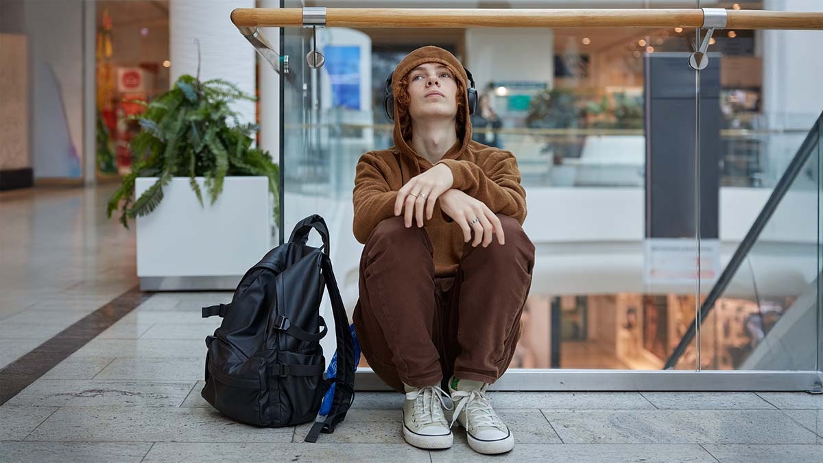 A young man sits on the ground, looking up in sadness