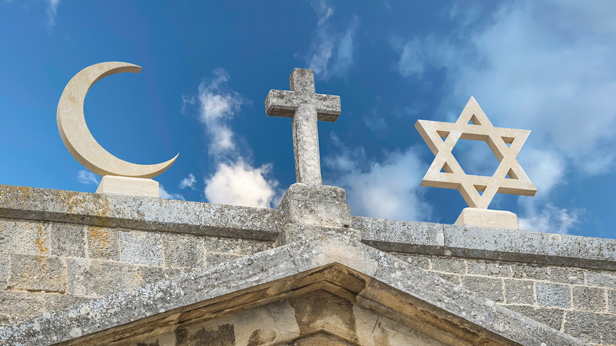 Symbols for Islam, Christianity, and Judaism sit on top of an old building