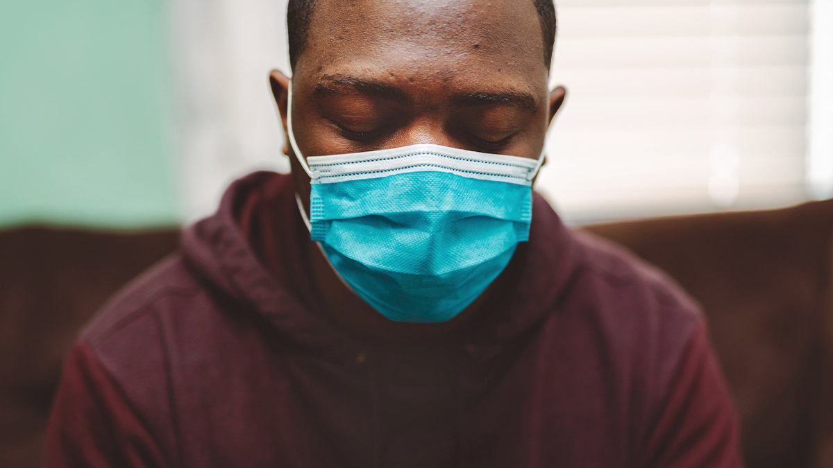 A man wearing a medical mask looks sad