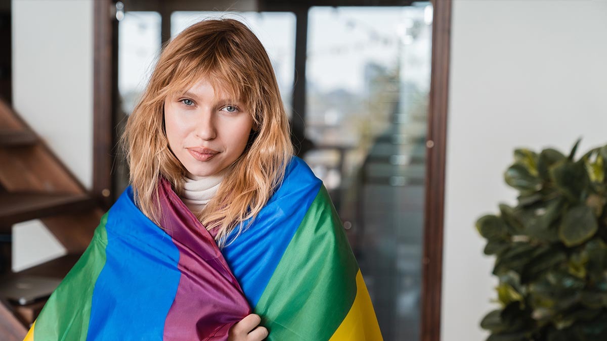 A woman wears a gay pride flag around her shoulders