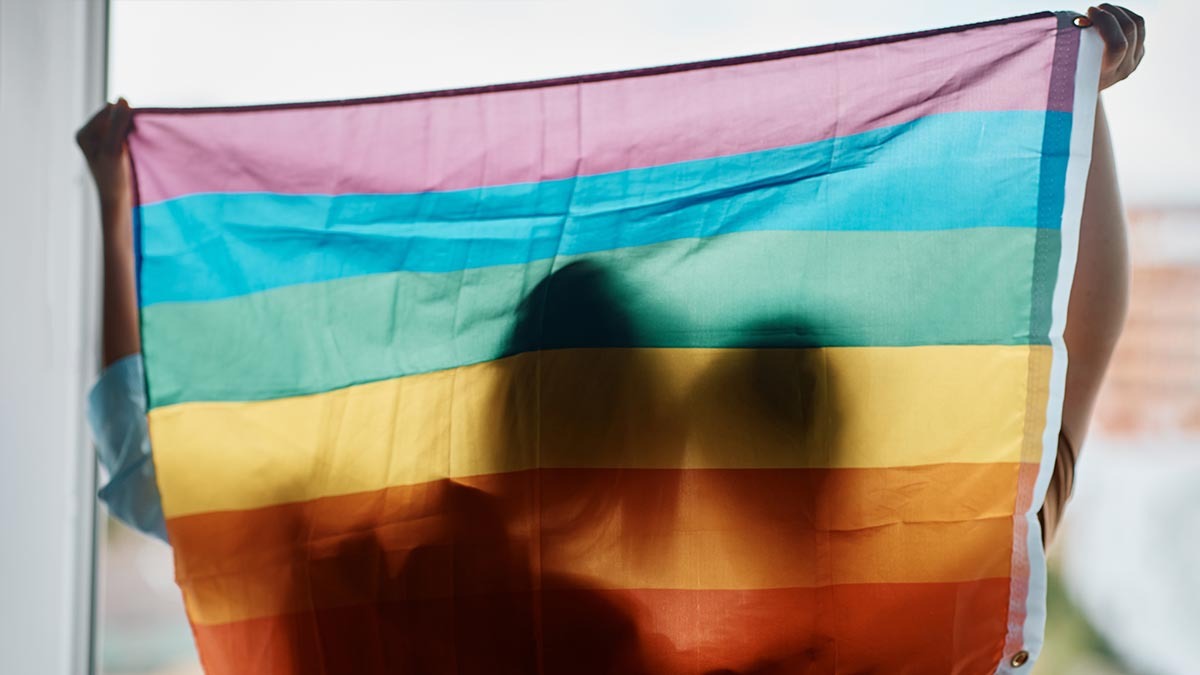 The silhouettes of two women can be seen through a gay pride flag