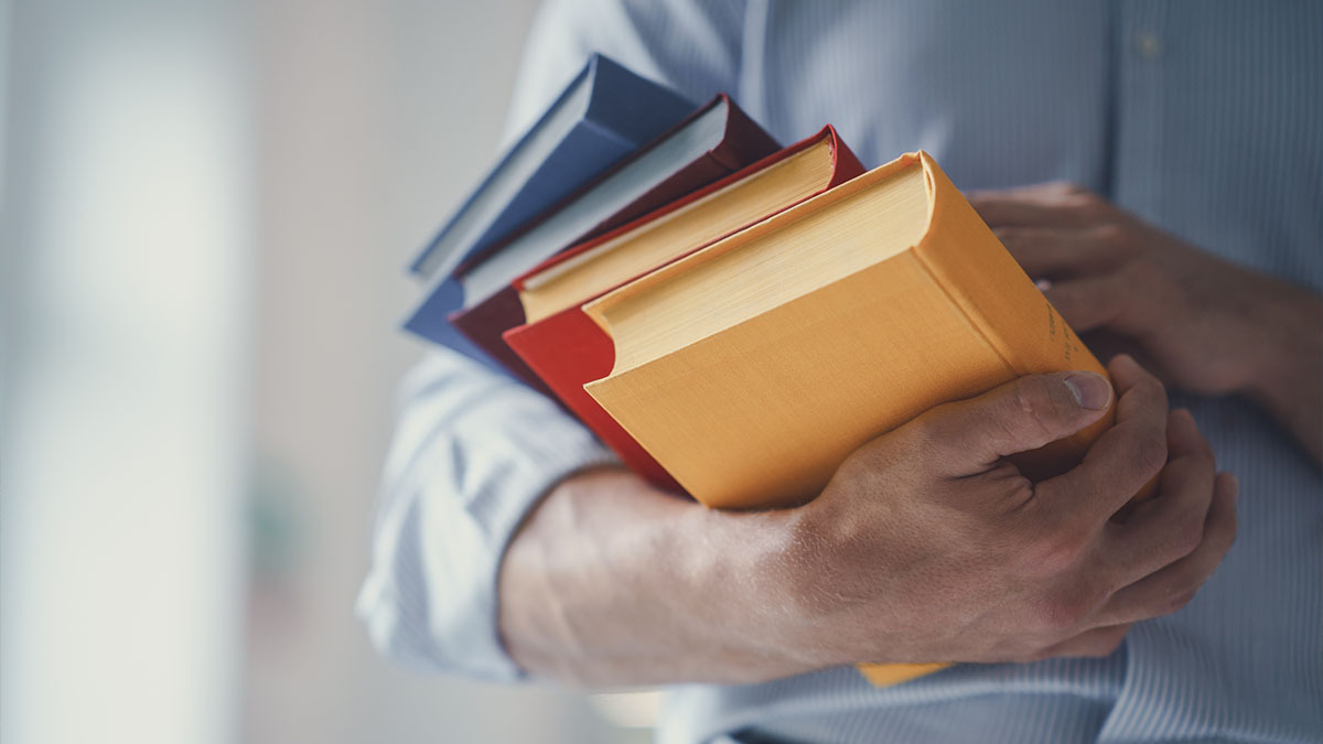 A man holds a stack of books