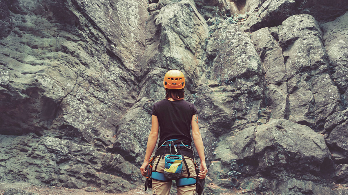 A rock climber looks at a threatening cliff in front of her