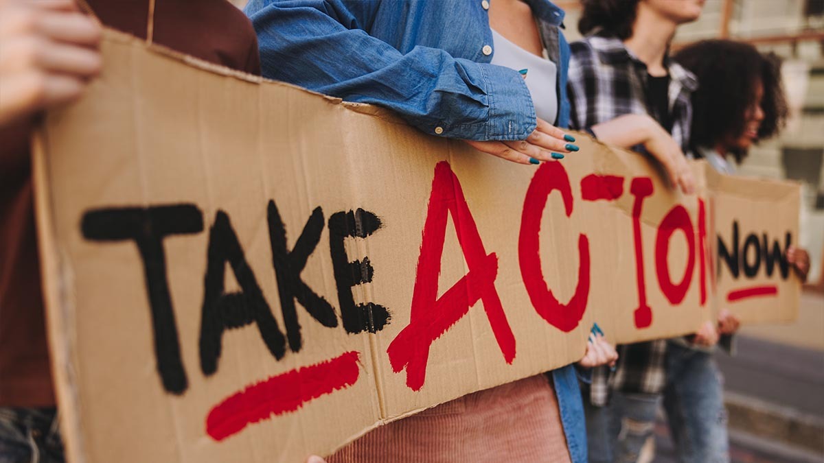 Protesters hold a sign that reads "take action now"