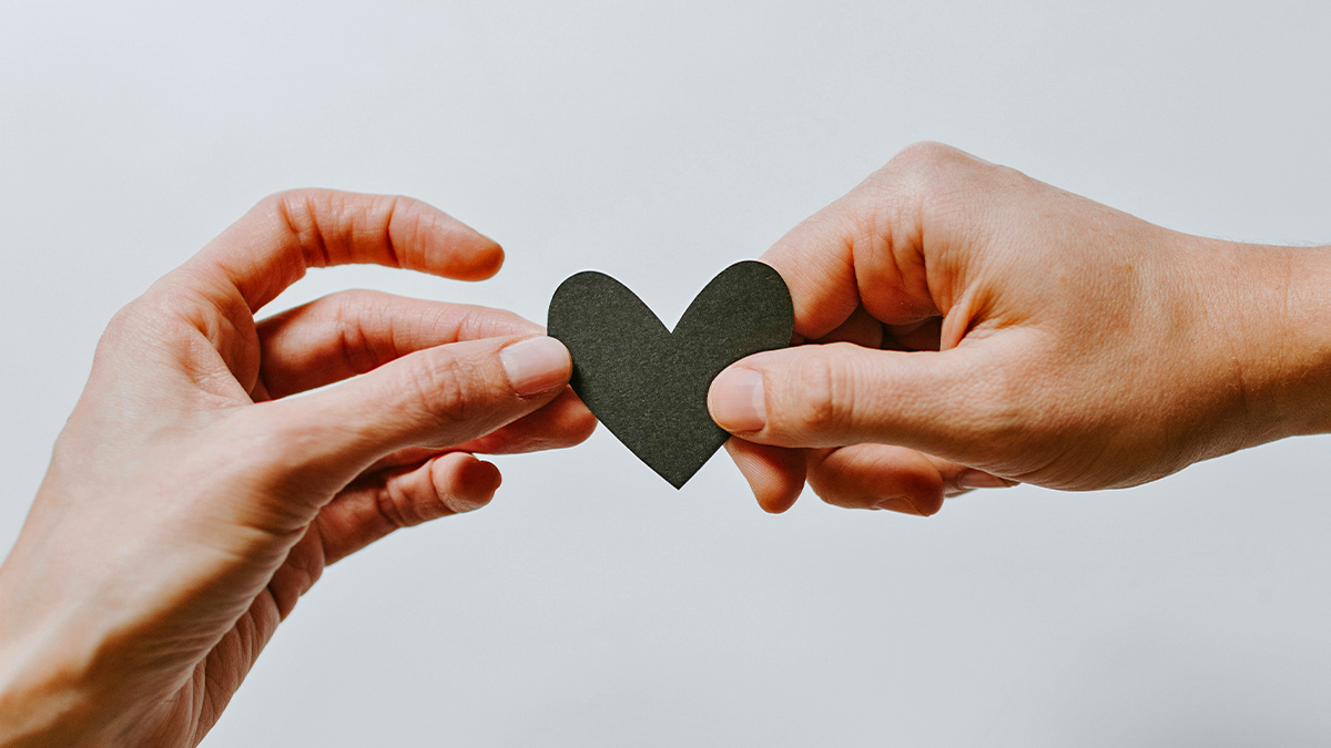 A person hands another person a paper heart