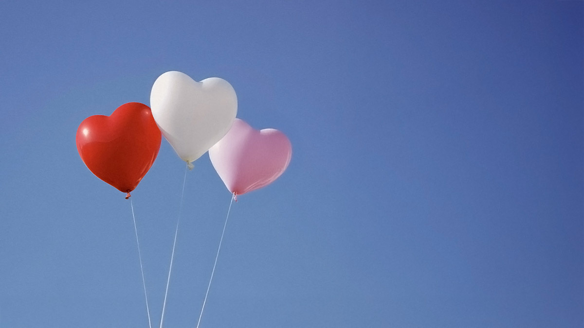 3 heart shaped balloons float in the sky