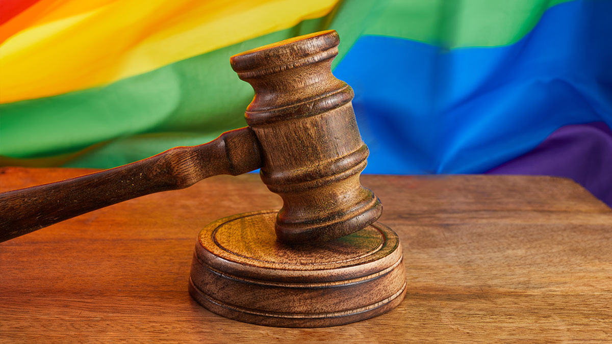 A gavel rests on a table in front of a gay pride flag