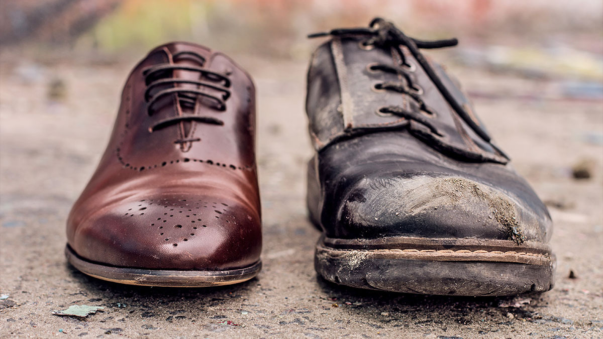 A pair of shoes. One shoe is shiny and polished, while the other shoe looks tattered and worn.