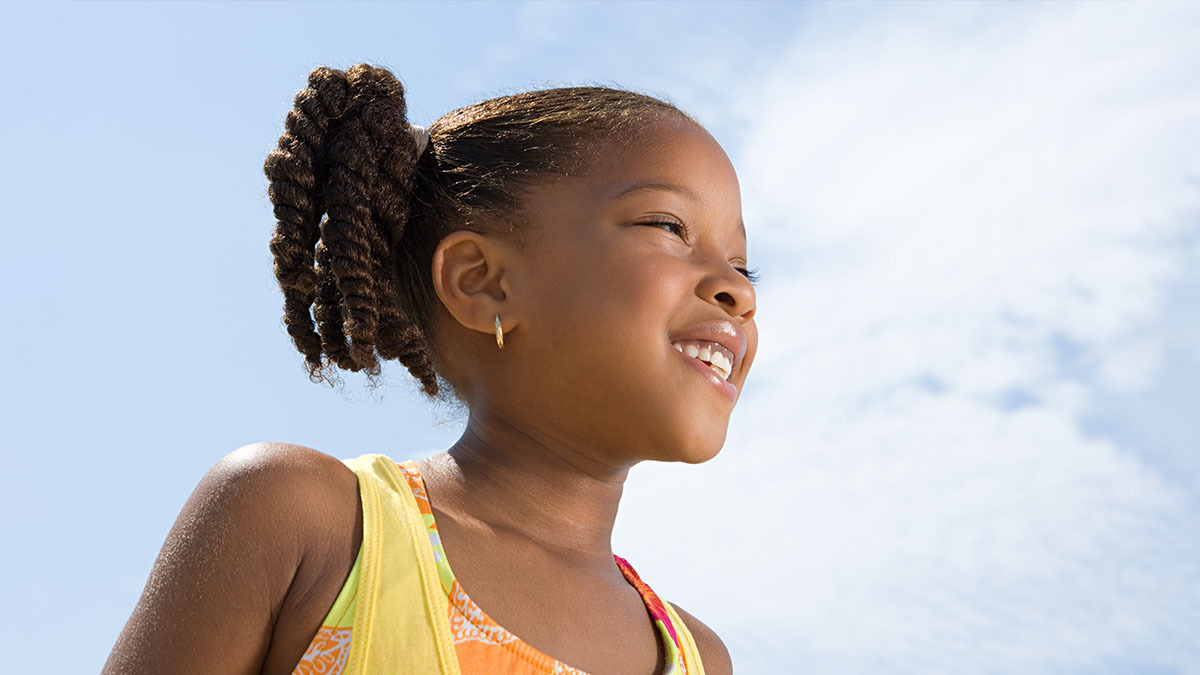 A little girl smiles and looks at the sky