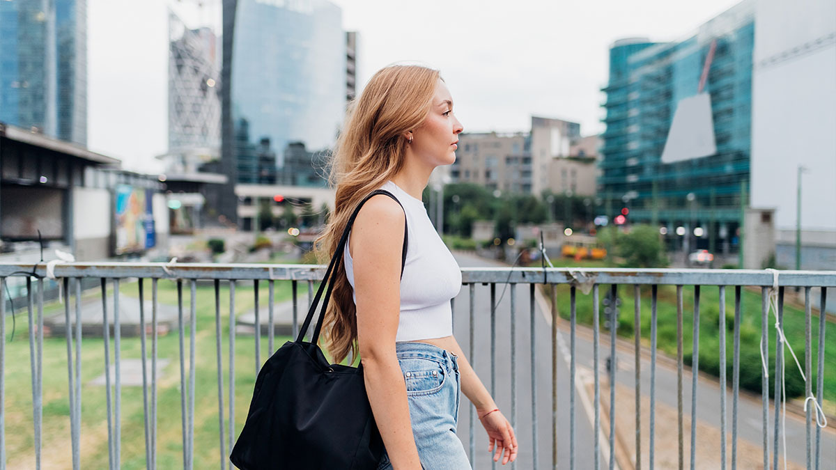 A young woman walking across a bridge in the city