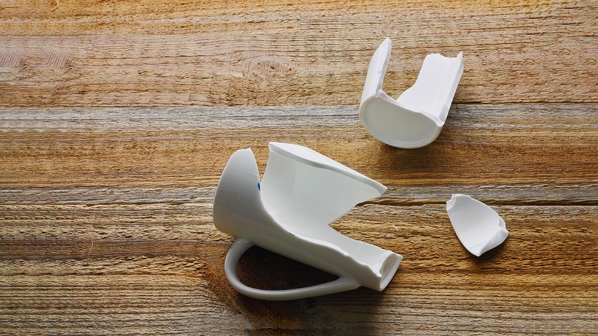 A broken coffee mug lies on the table in pieces
