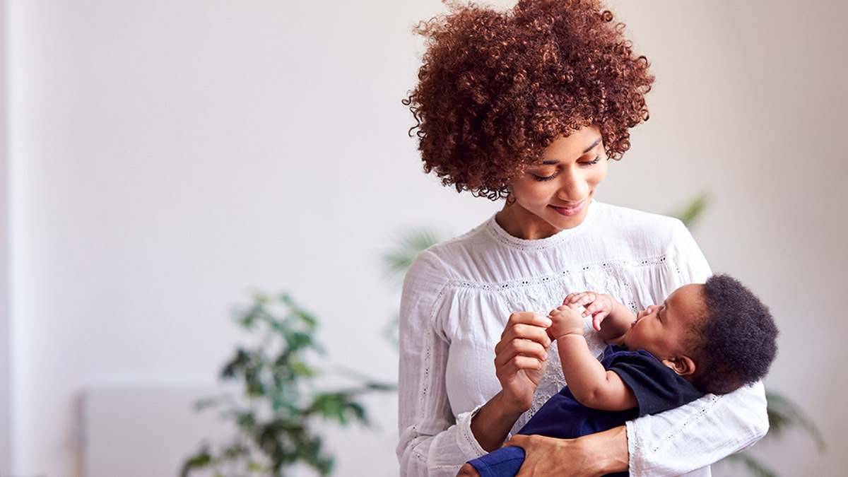 A mother lovingly looks down at her baby as she cradles him