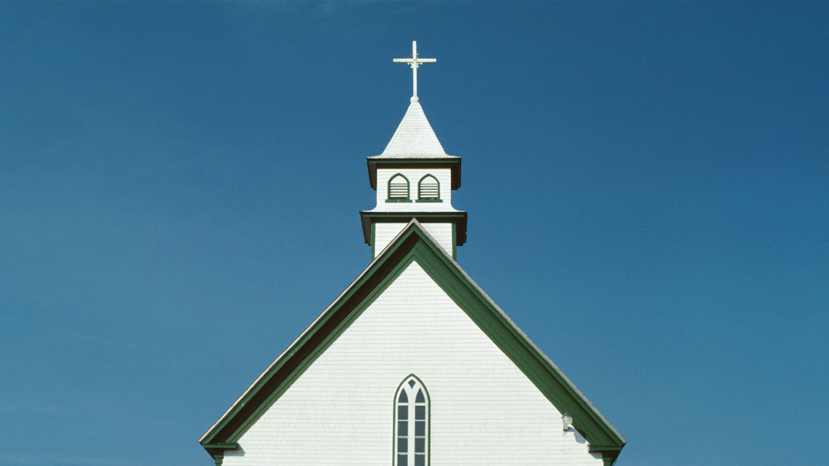 A church with a steeple stands against a blue sky
