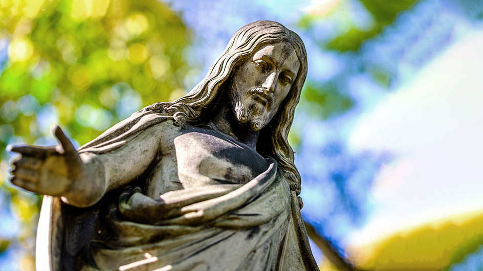 A statue of Jesus Christ in a lush, green park