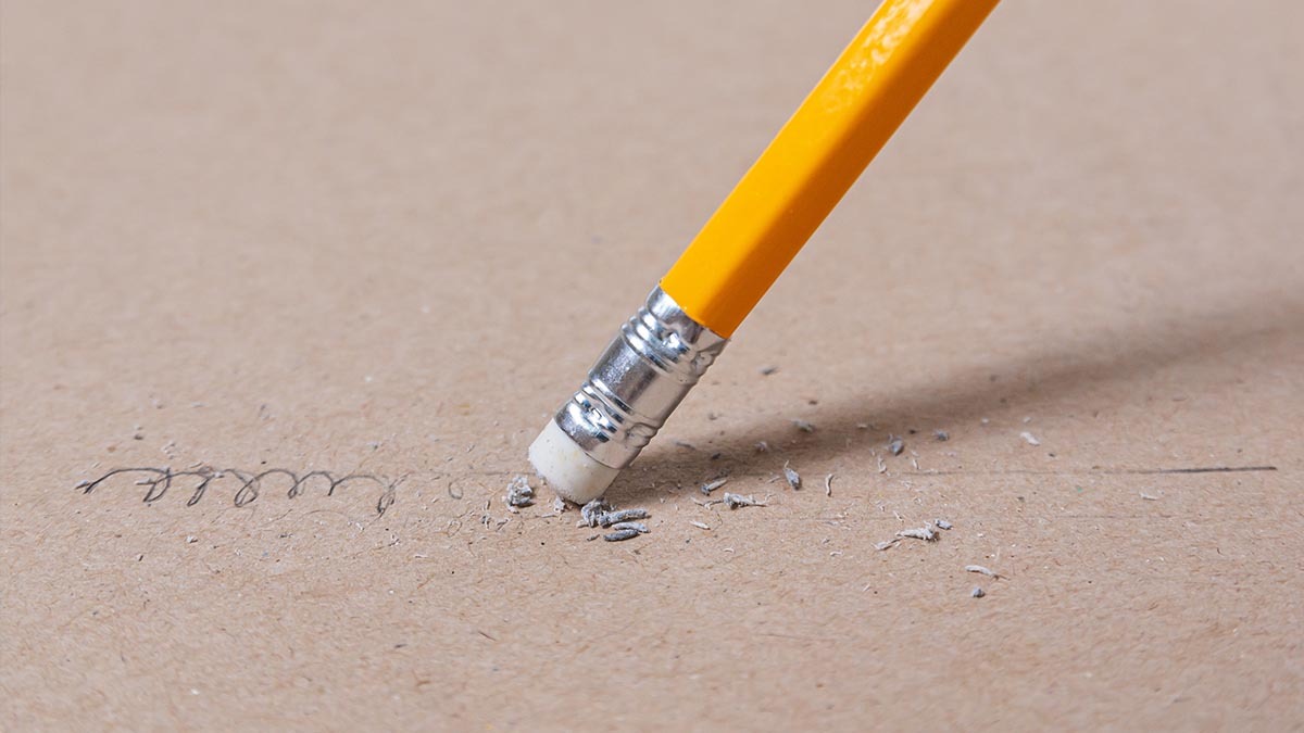 A pencil eraser erases a word off of a piece of paper