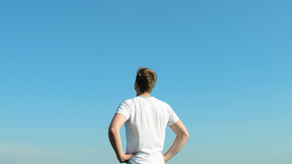 A man looks off into a big blue sky