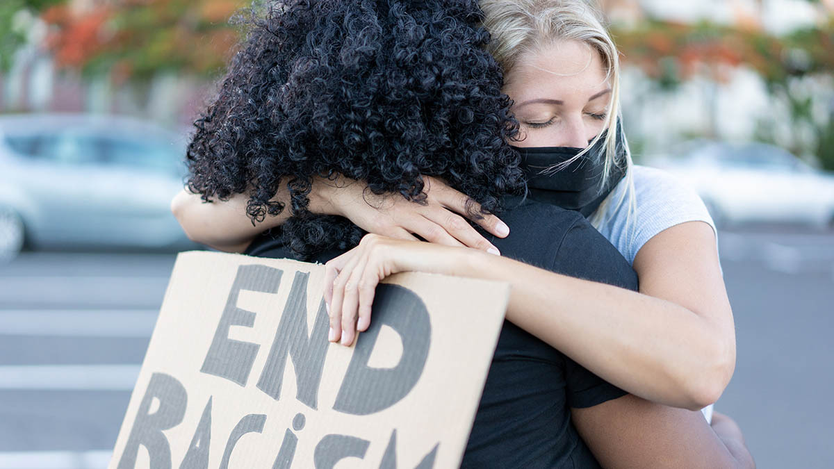A white protester and black protester hug each other