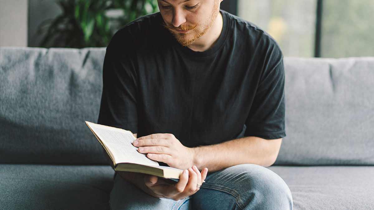 A young man looks down at an open Bible in his hands