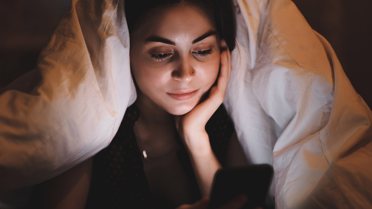 A young girl scrolling on her phone at night in bed