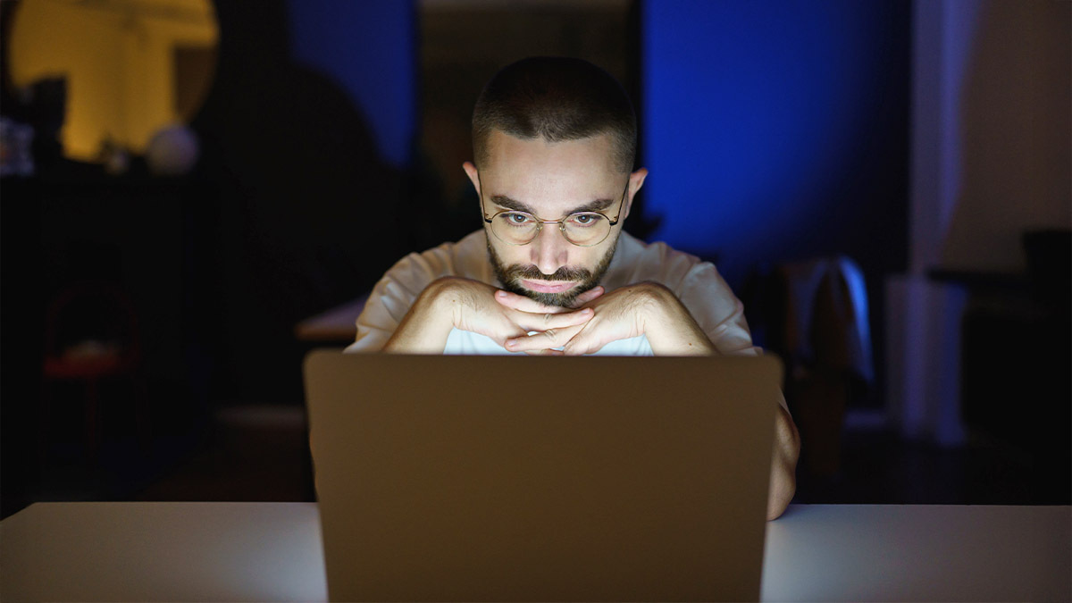 A man stays up late watching a video on his computer