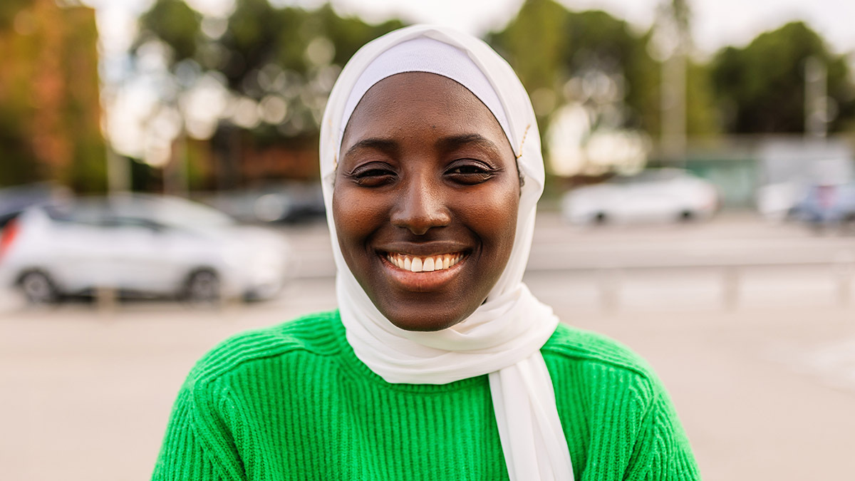 A Muslim girl wearing a hijab smiles at the camera