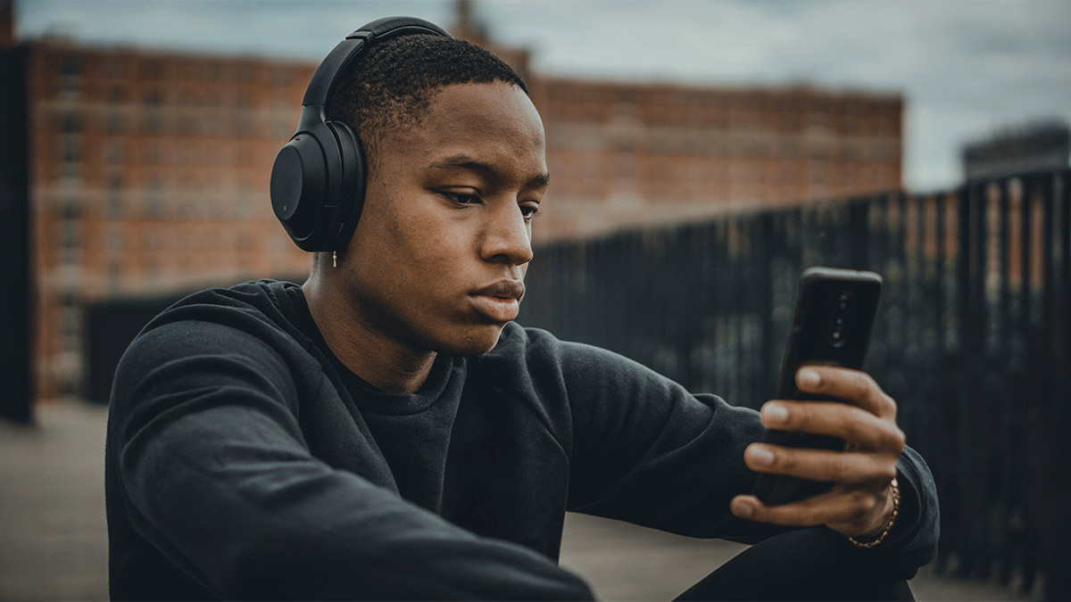 A young man listens to a podcast with his headphones