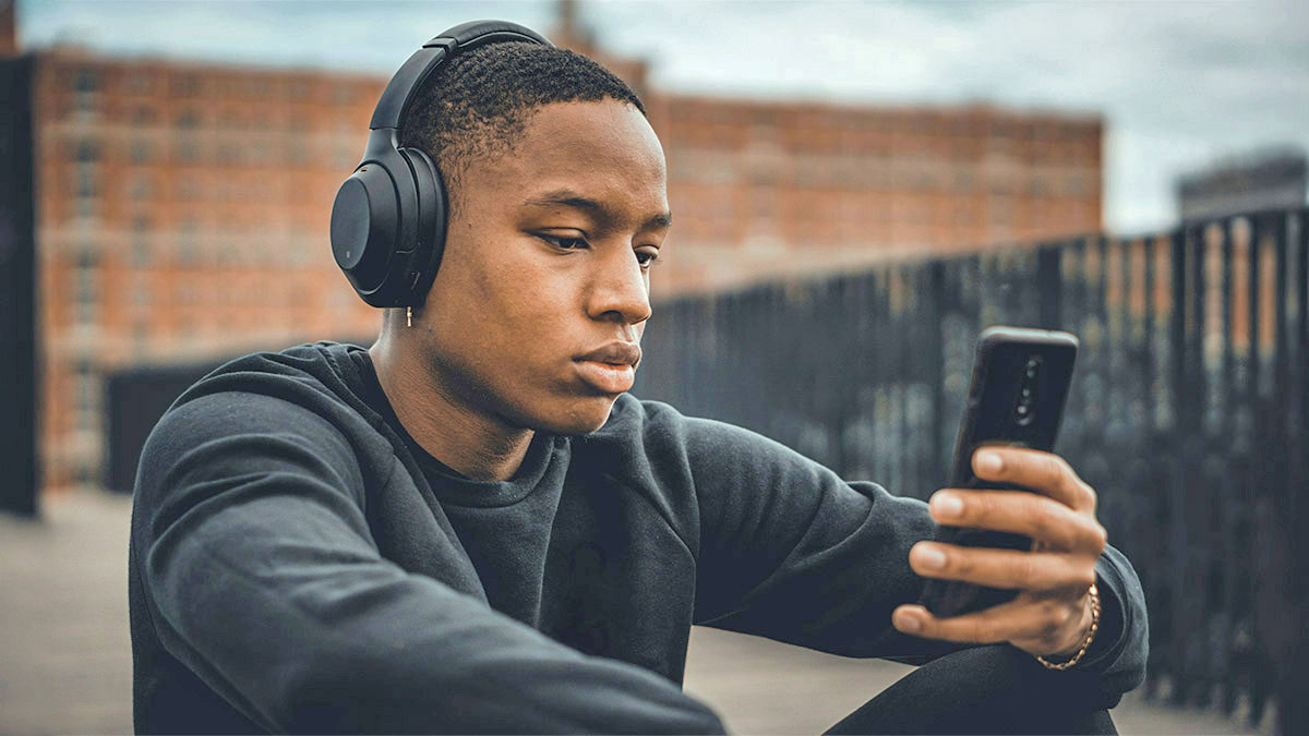 A young man listens to a podcast with his headphones