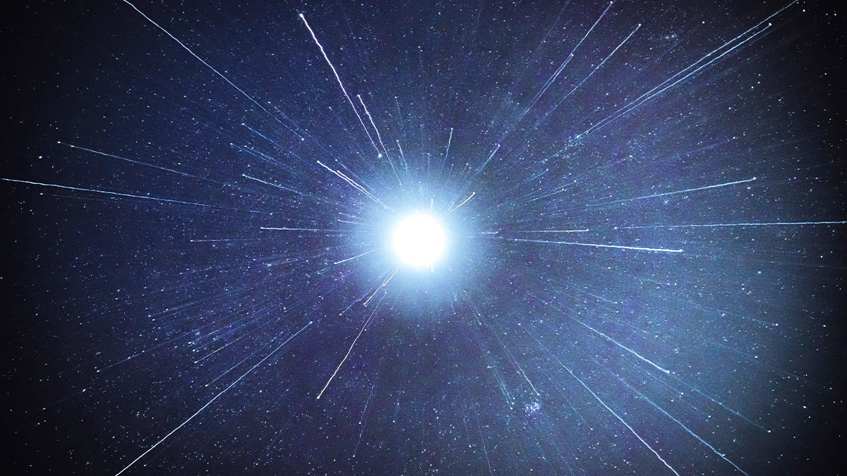 A bright light shines in a dark, starry sky